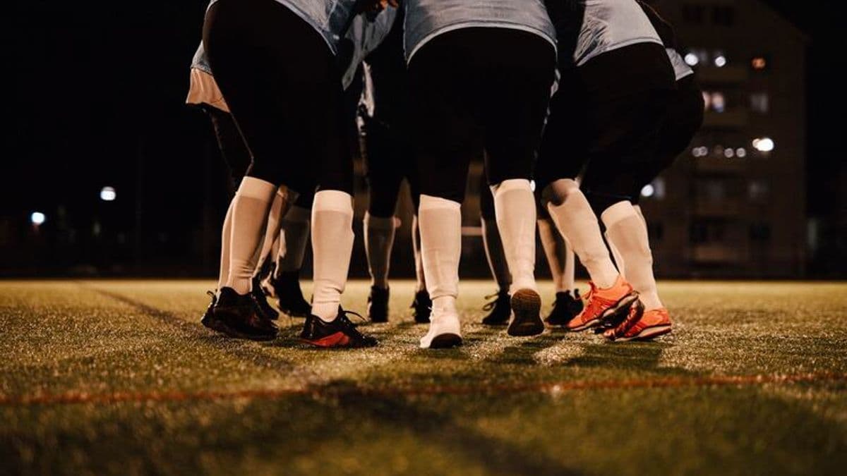 Low section of female soccer team huddling together on field at night