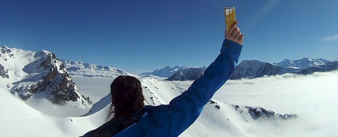 Charlotte Evans on top of mountain skiing with hand in the air
