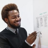 Man holding pen to whiteboard and smiling